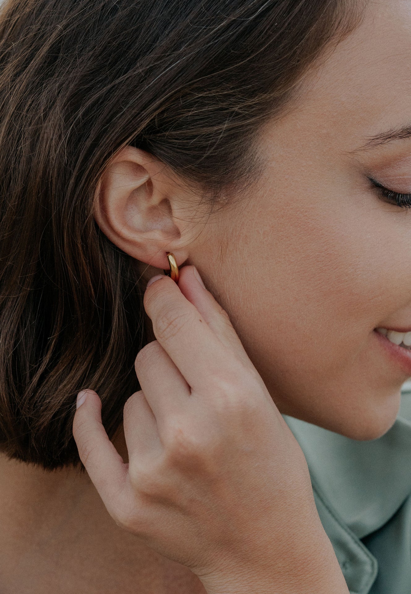 Close-up of a woman wearing a gold earring.