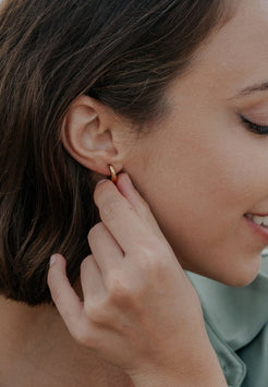 Close-up of a woman wearing a gold earring.