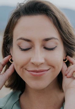 Woman wearing gold hoop earrings with a blurred background