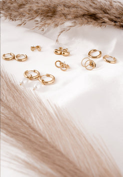 Collection of gold earrings on a soft white fabric background