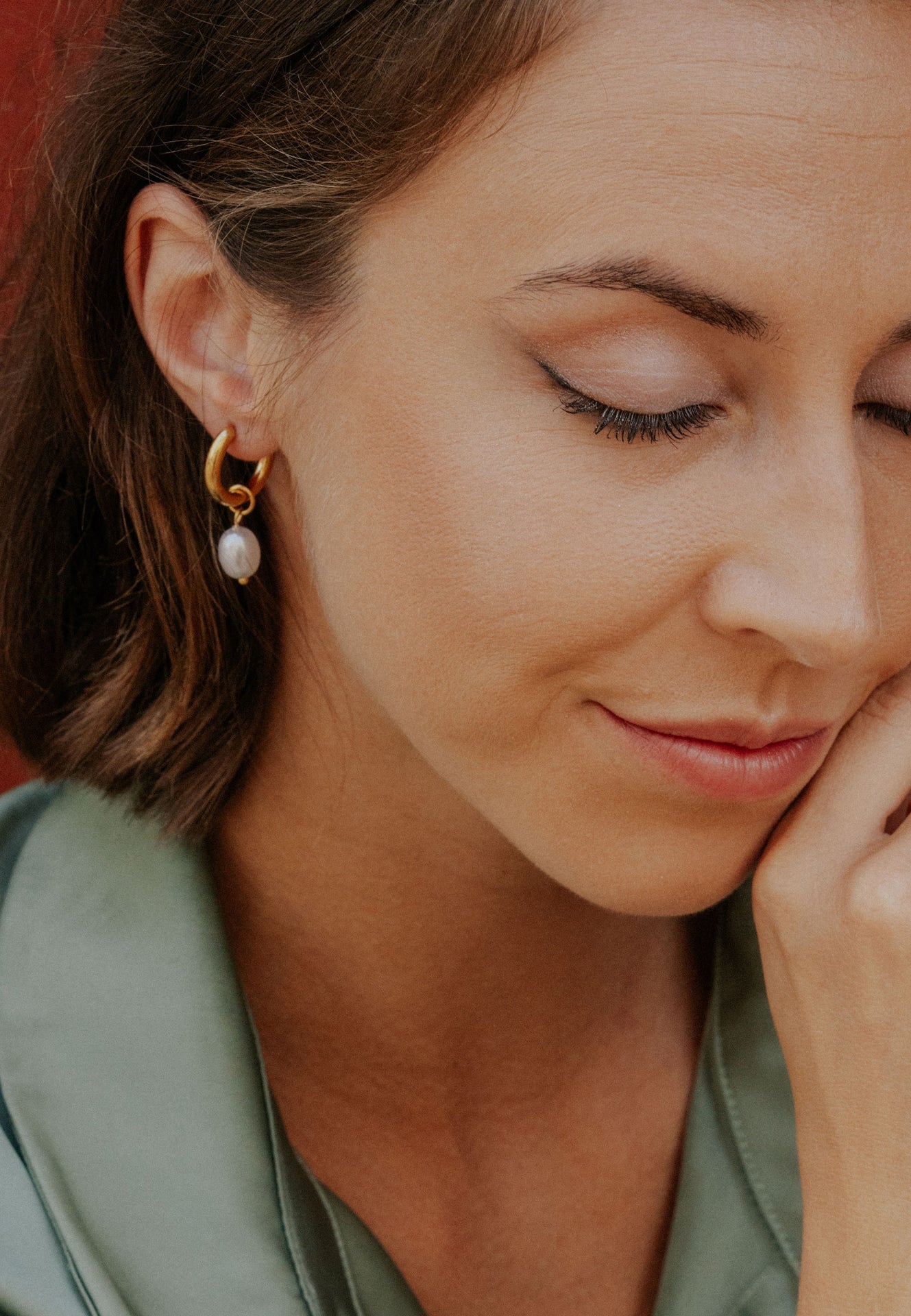 Close-up of a woman wearing pearl earrings with a blurred background