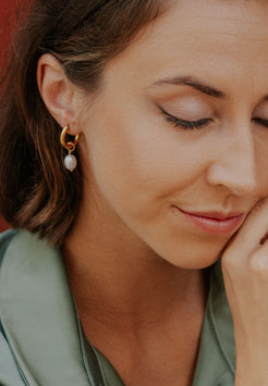 Close-up of a woman wearing pearl earrings with a blurred background