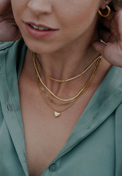 Close-up of a person wearing gold necklaces and earrings, with a green shirt.