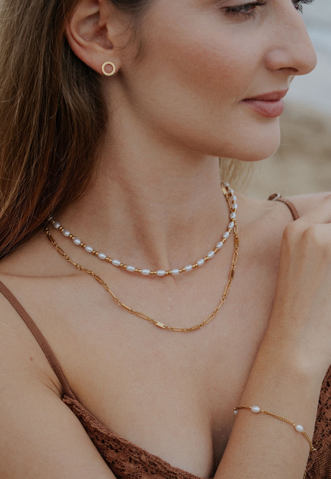 Woman wearing a gold necklace and earrings with a blurred background