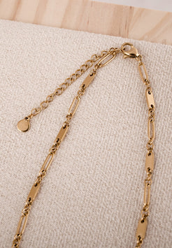 Gold chain bracelet on a beige fabric background