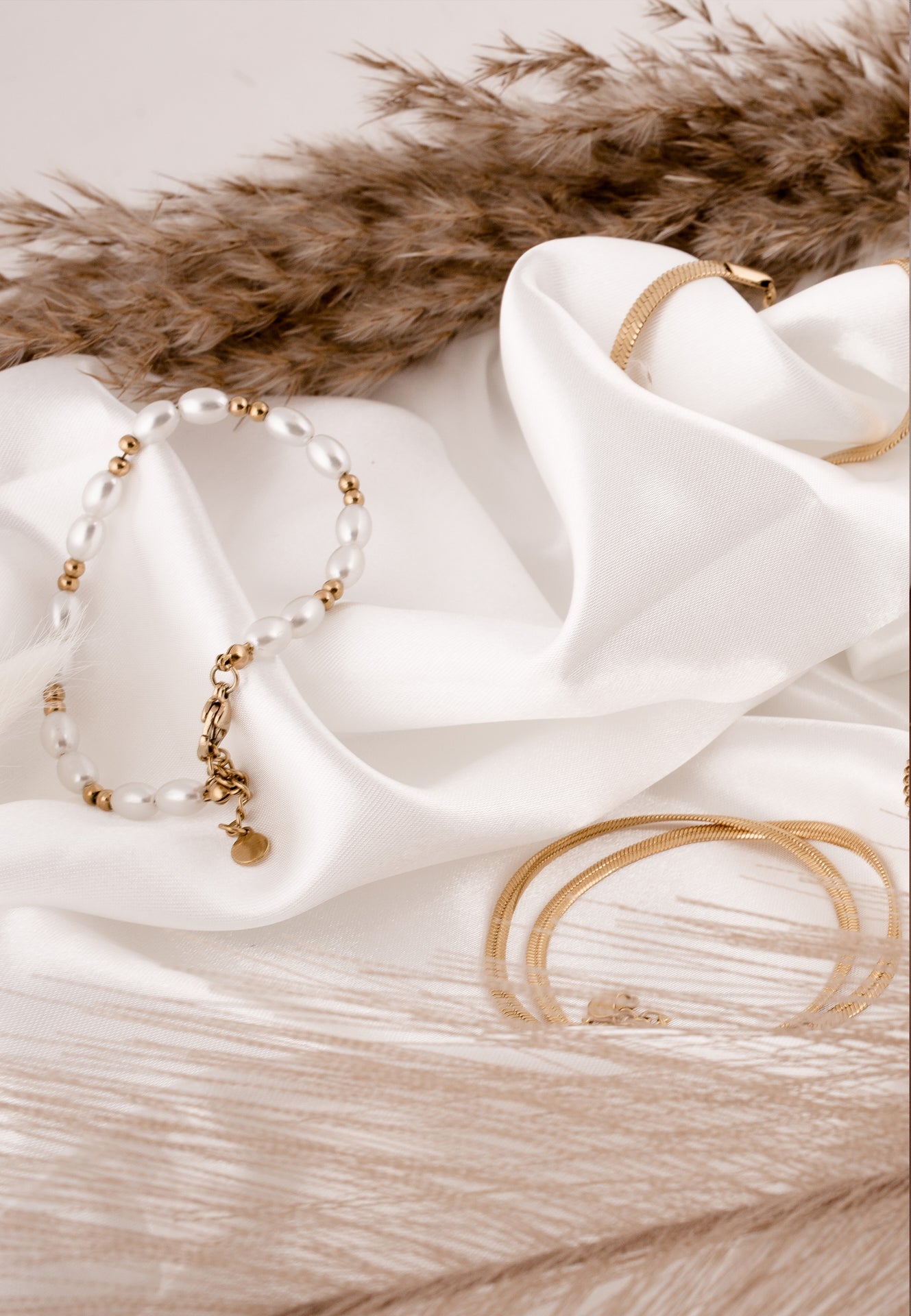 Gold bracelet and ring on white fabric with brown fur background
