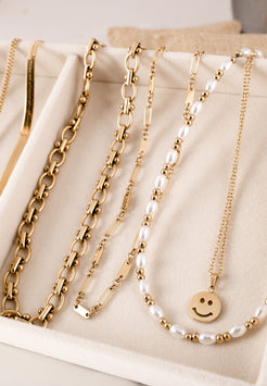 Gold and pearl necklaces on a beige surface