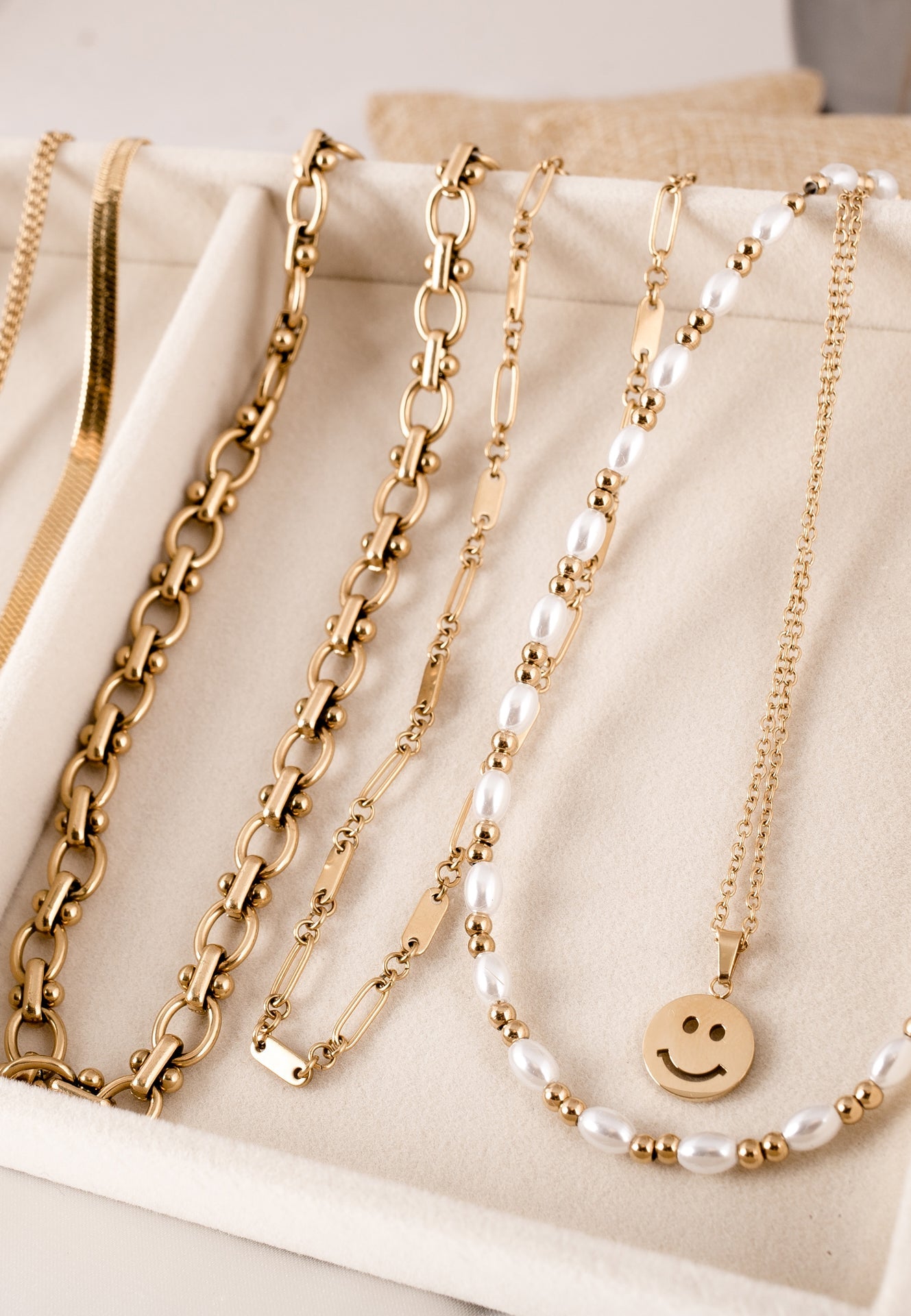Gold and pearl necklaces on a beige surface