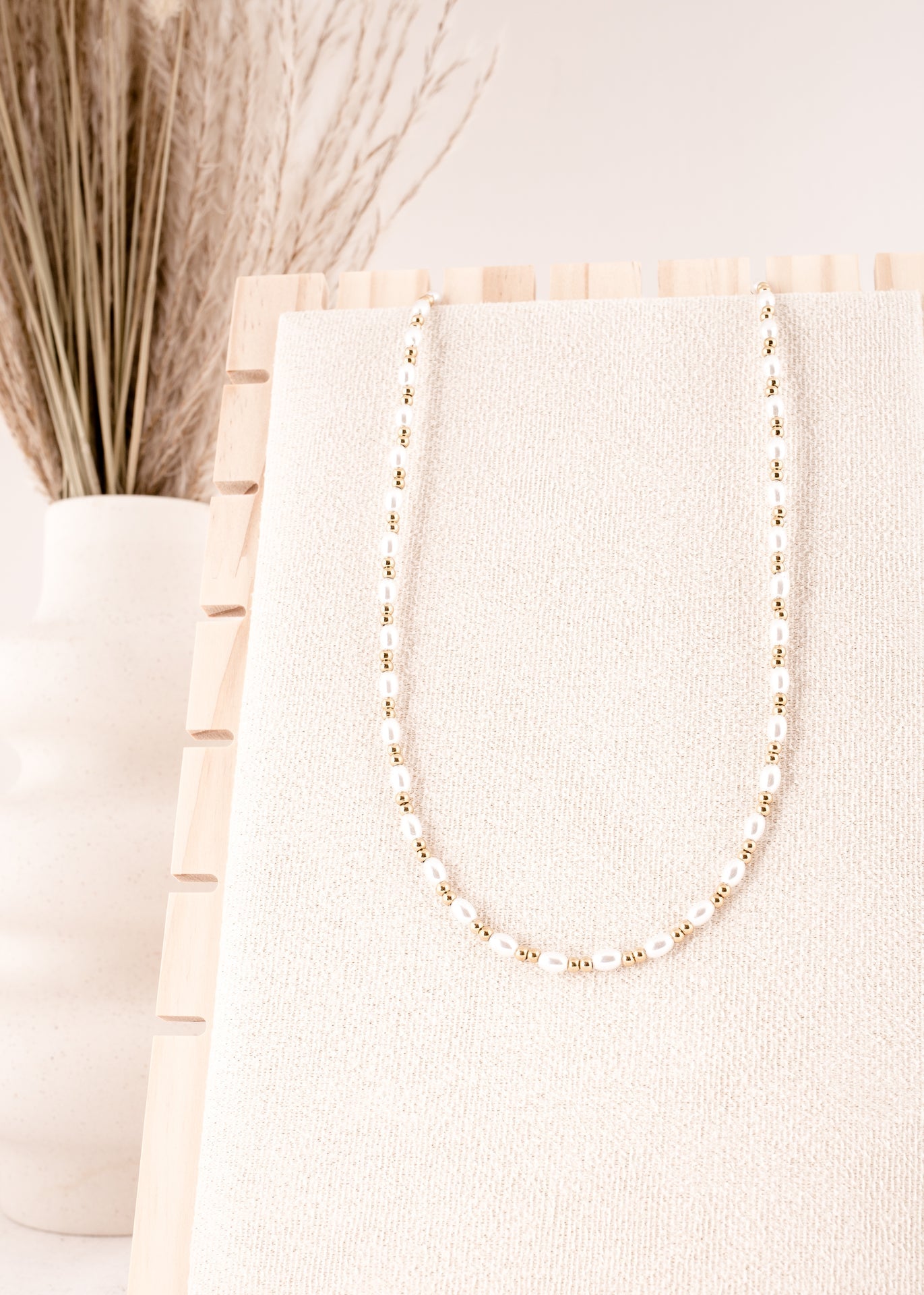 Pearl necklace on a white surface with a neutral background