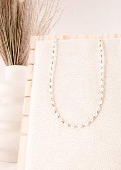 Pearl necklace on a white surface with a neutral background