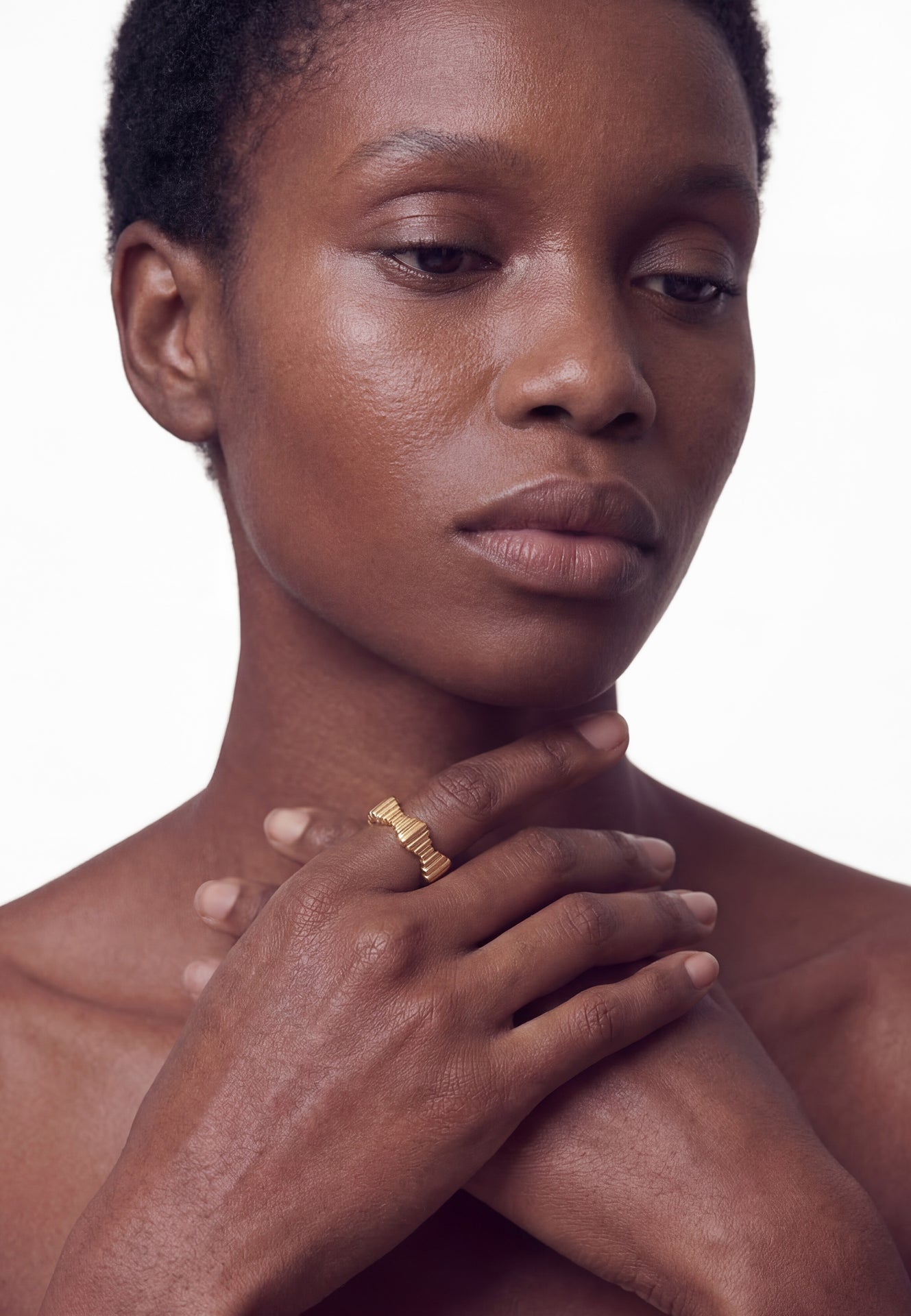 Close-up of a person with a gold ring on their finger against a white background