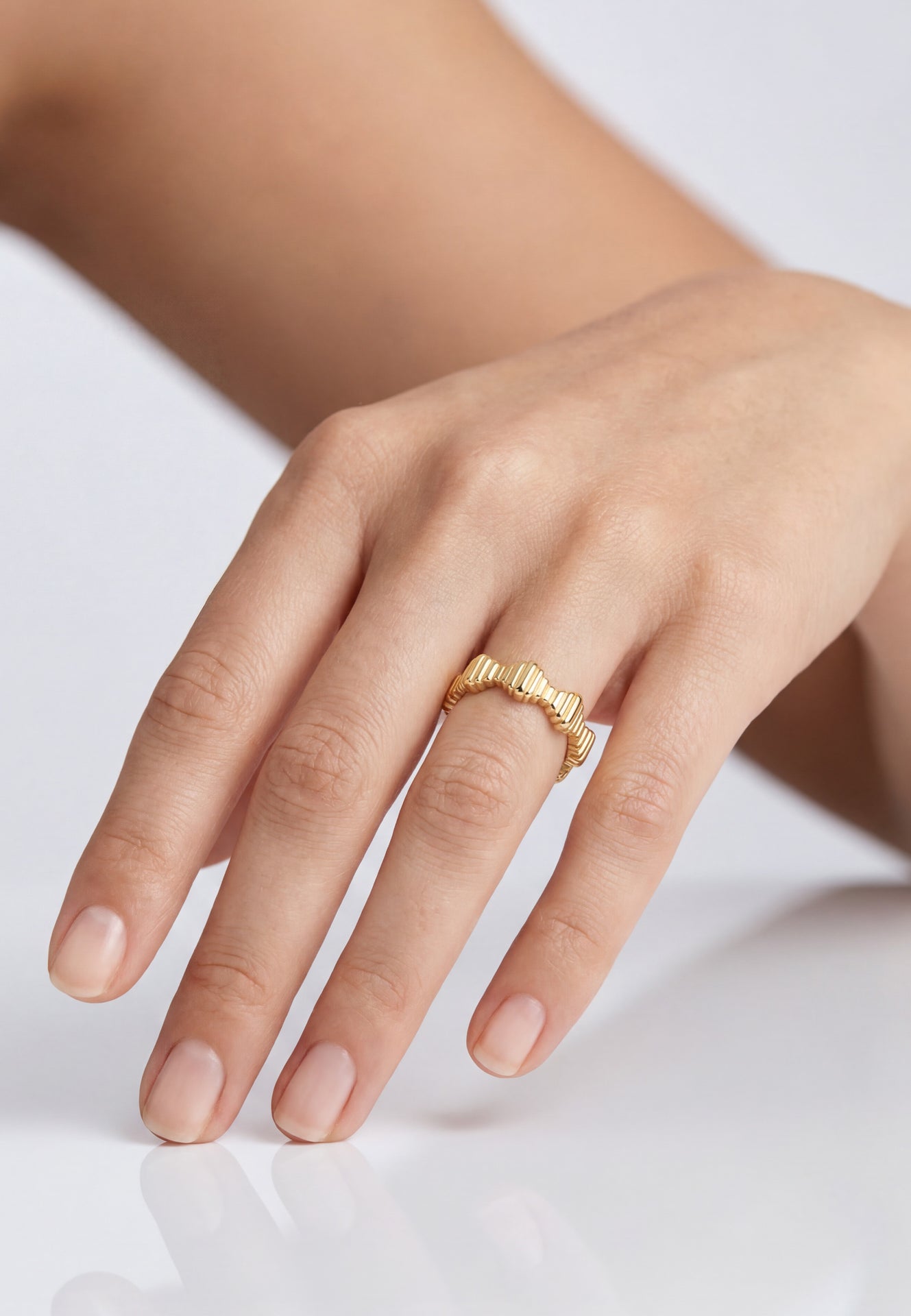 Gold ring on a person's finger against a white background
