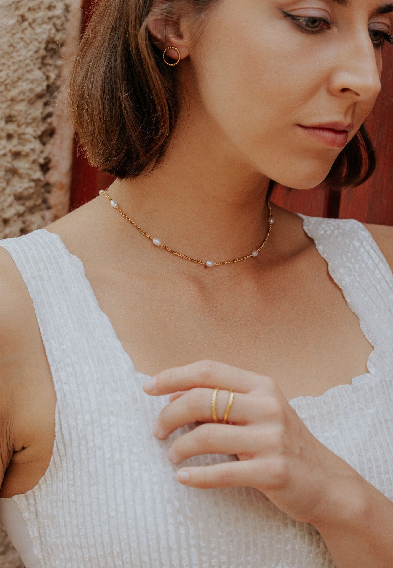 Woman wearing a pearl necklace and gold ring with a blurred background