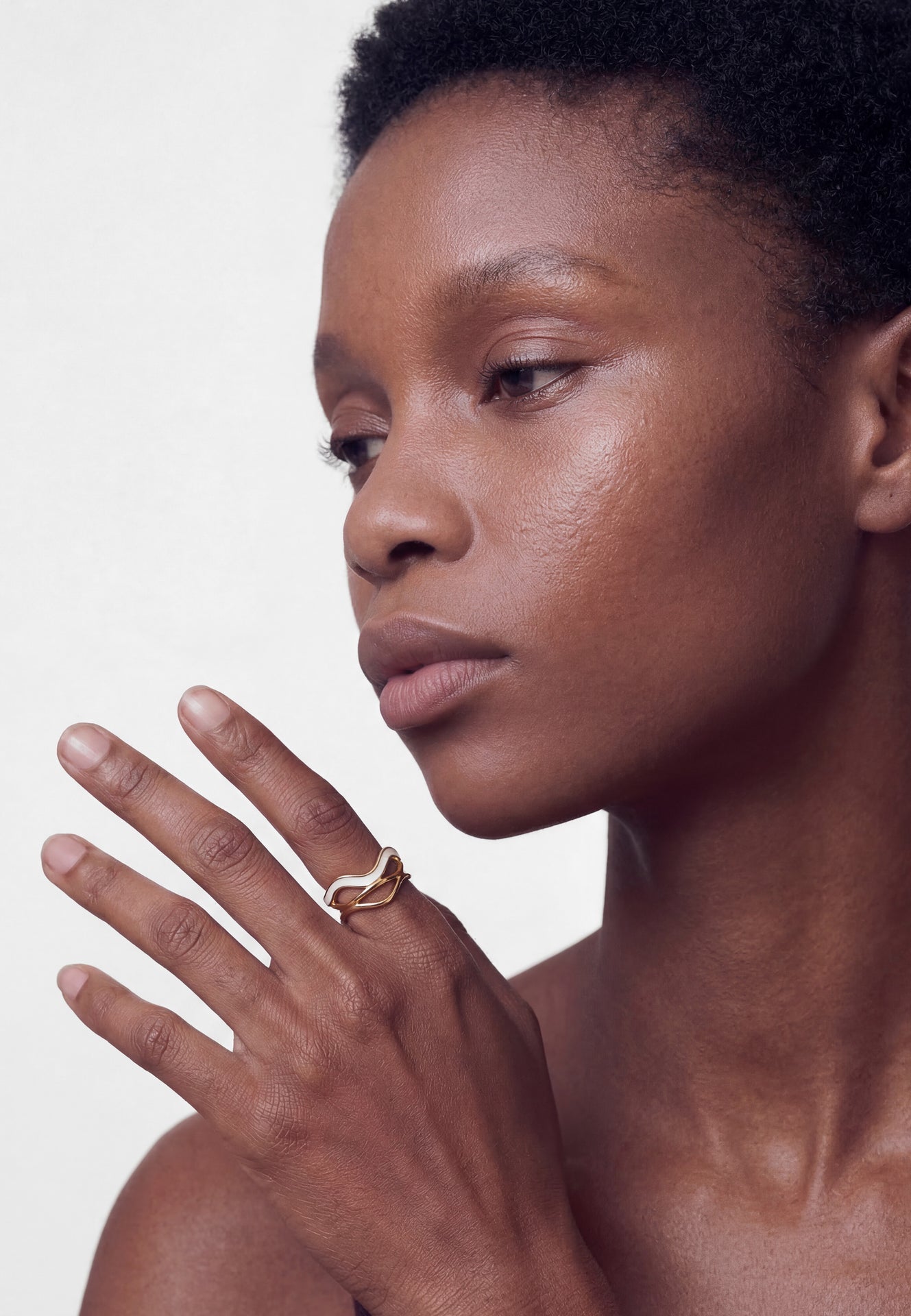Close-up of a person with a gold ring on their finger against a neutral background