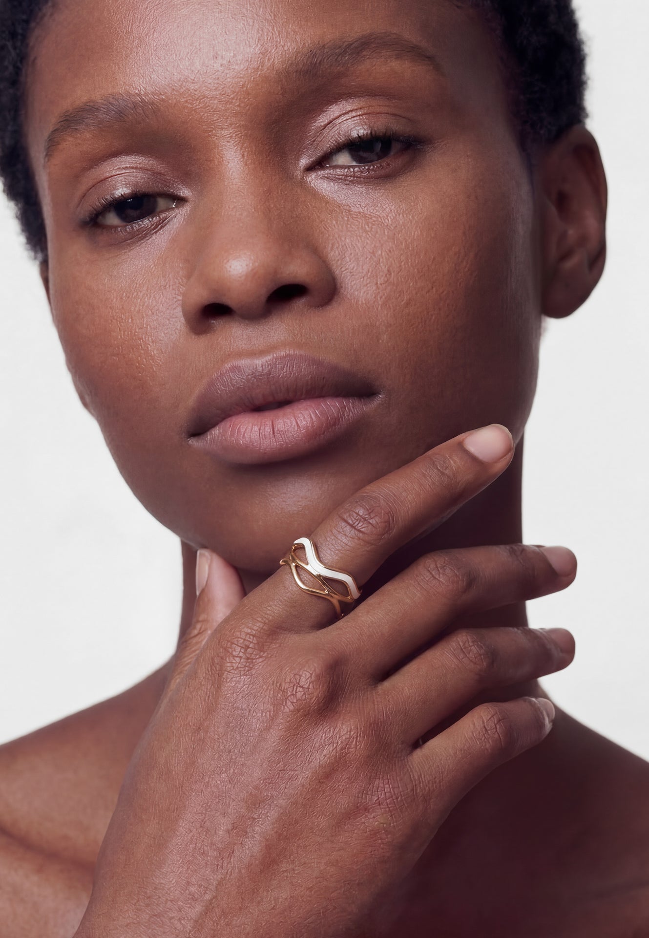 Close-up of a person wearing a gold ring on a plain background