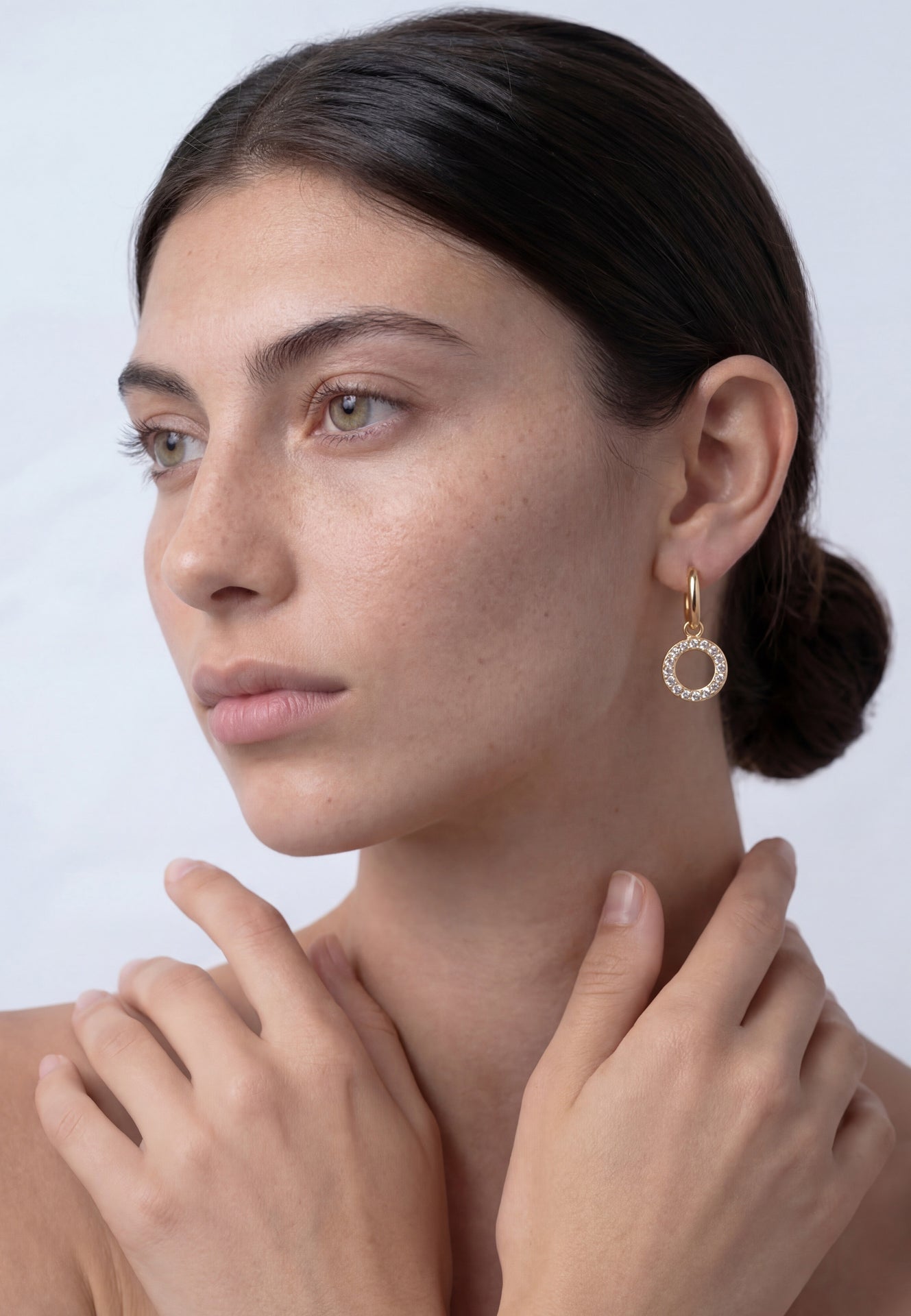 Woman wearing a gold hoop earring against a white background