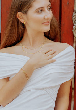 Woman wearing gold jewelry against a red wooden background