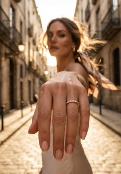Woman holding out hand with gold ring on a sunlit street