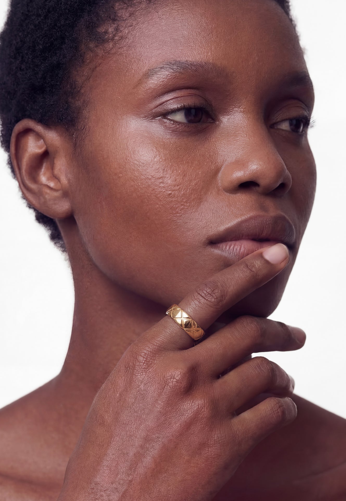 Close-up of a person with a gold ring on their finger against a white background
