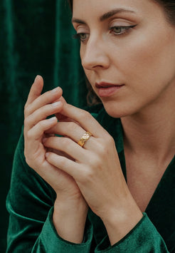 Woman wearing a gold ring with a green background
