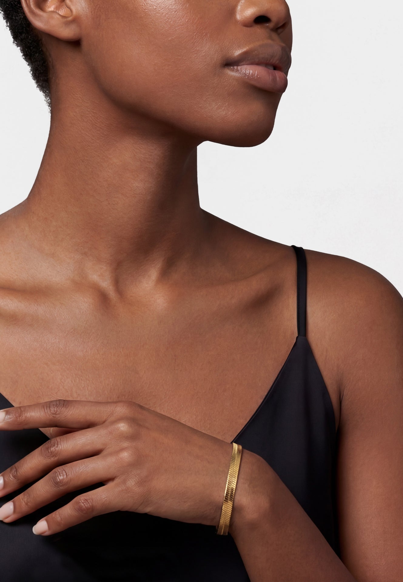 Woman wearing a gold bracelet on a plain background