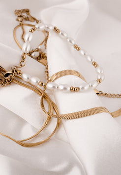 Gold and pearl jewelry set on a white fabric background