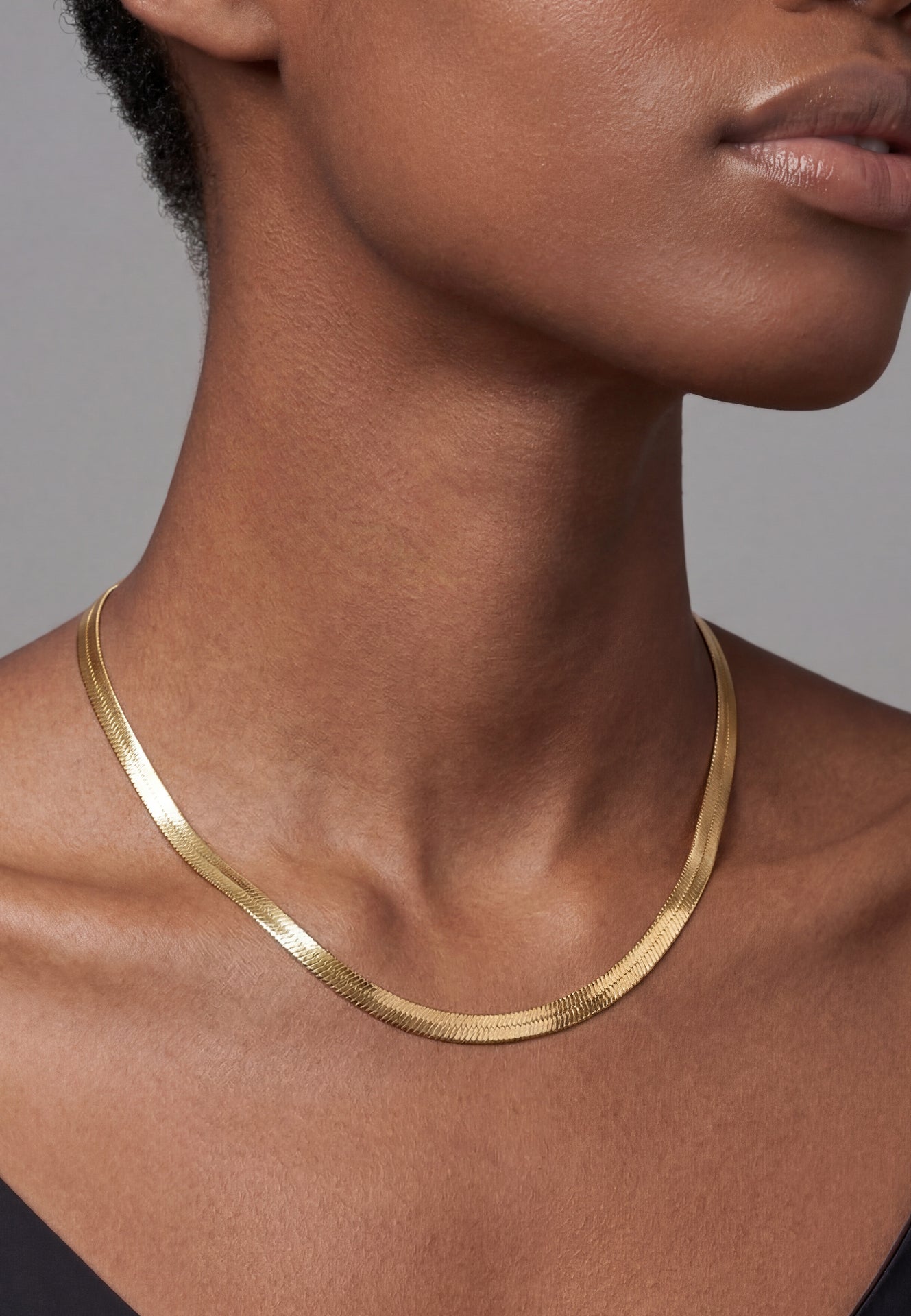Gold necklace on a person against a neutral background