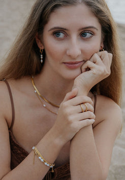 Woman wearing gold jewelry with a neutral background