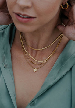 Close-up of a person wearing gold necklaces and earrings.