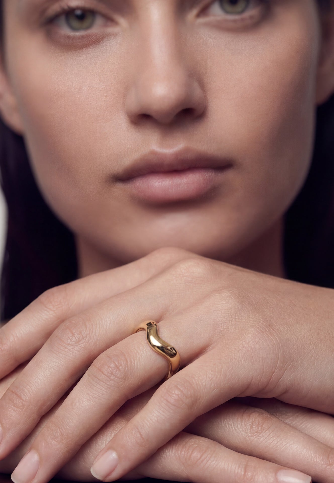 Close-up of a woman's hand wearing a gold ring with a dark background