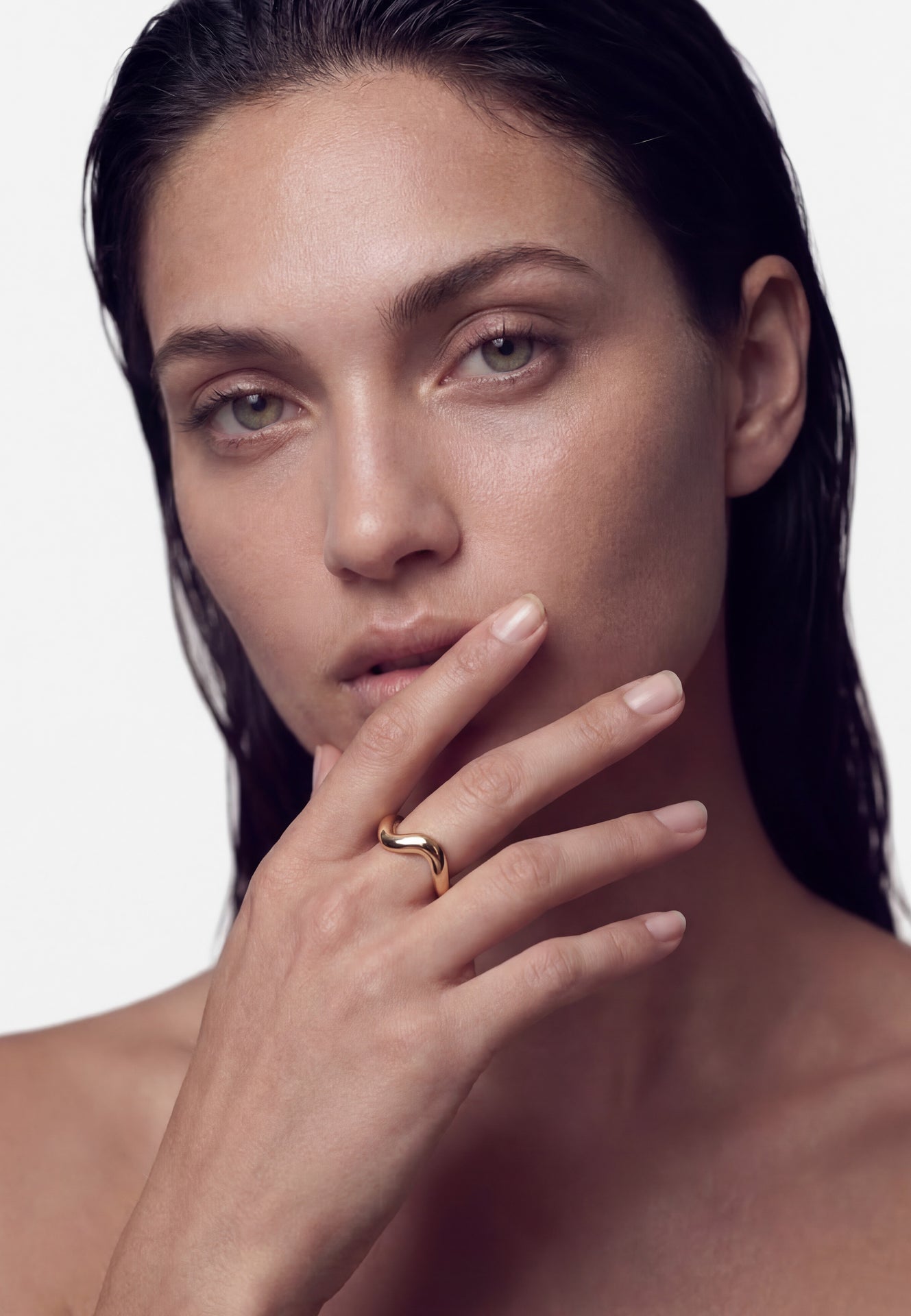 Woman with a gold ring on her finger against a white background