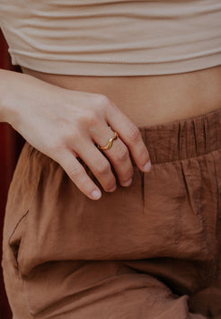 Close-up of a person wearing a gold ring on a blurred background