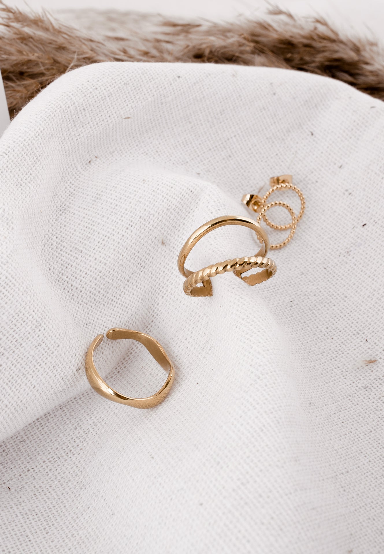 Gold hoop earrings on a white fabric background