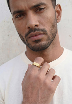 Man wearing a gold Akitsune ring against a neutral background
