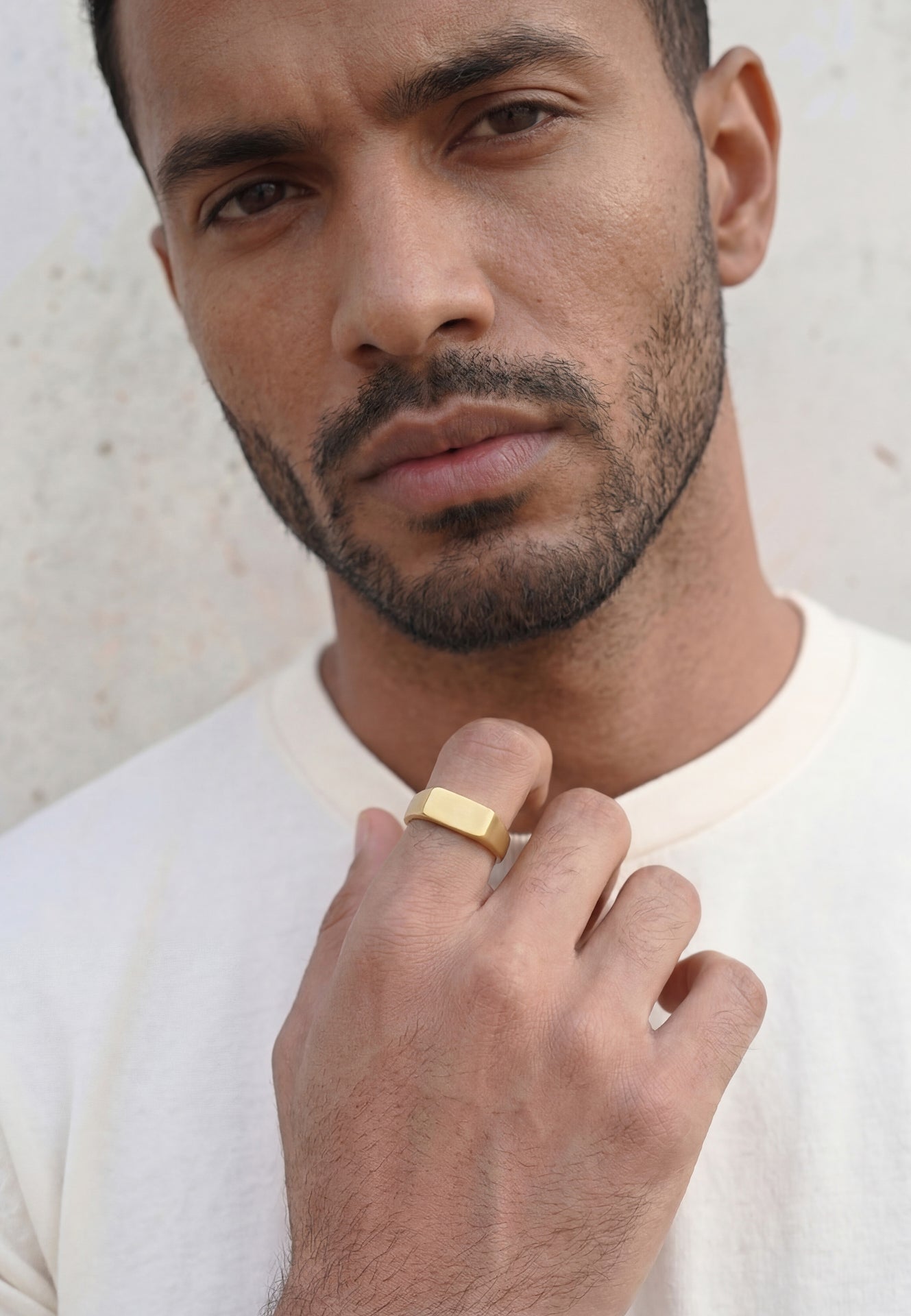 Man wearing a gold Akitsune ring against a neutral background