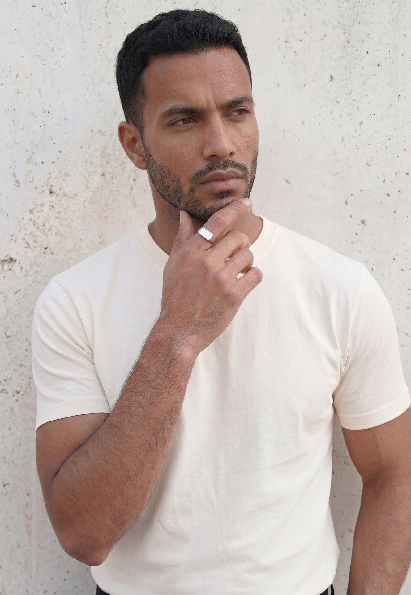 Man wearing a white t-shirt against a light gray wall