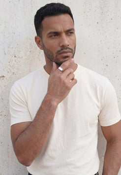Man wearing a white t-shirt against a light gray wall
