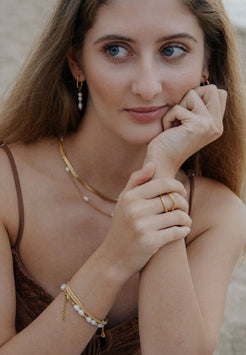 Woman wearing gold jewelry with a neutral background