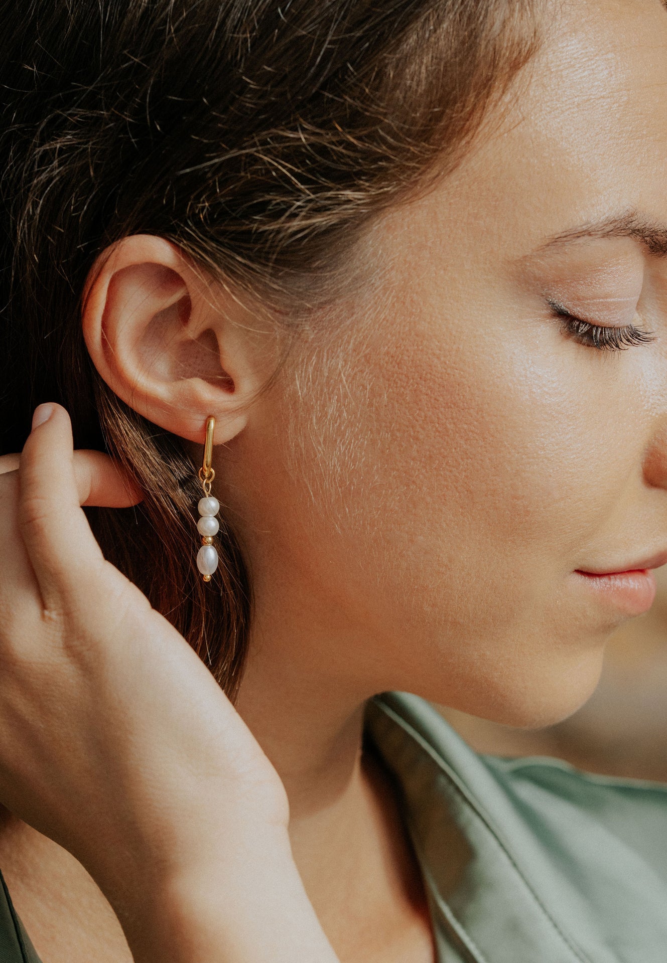 Close-up of a woman wearing pearl earrings with a soft focus background