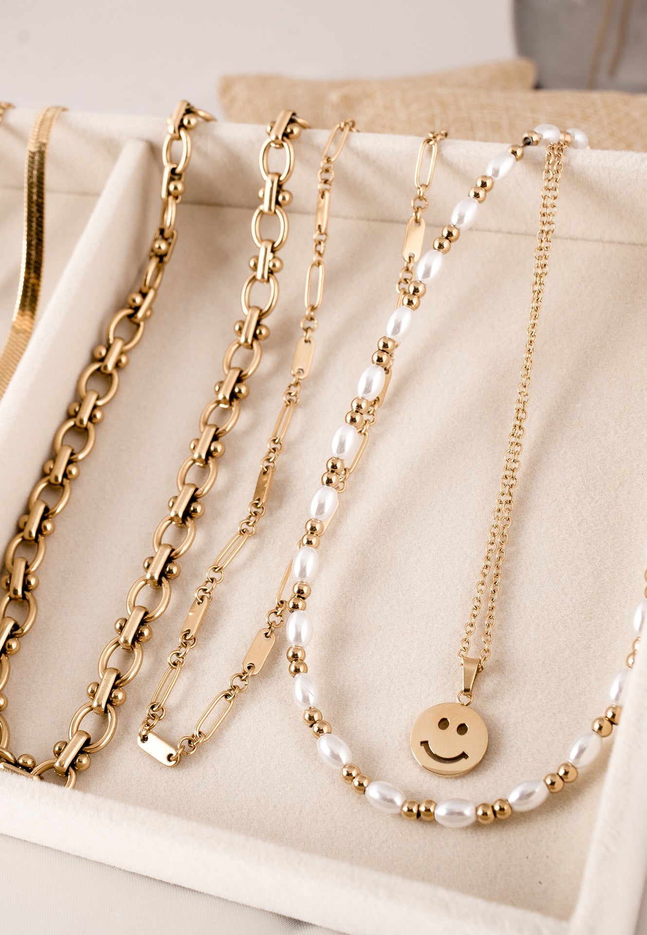 Gold and pearl necklaces on a beige surface