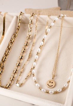 Gold and pearl necklaces on a beige surface