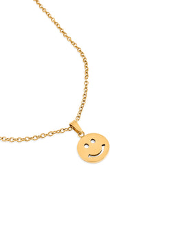 Gold necklace with a smiley face pendant on a white background