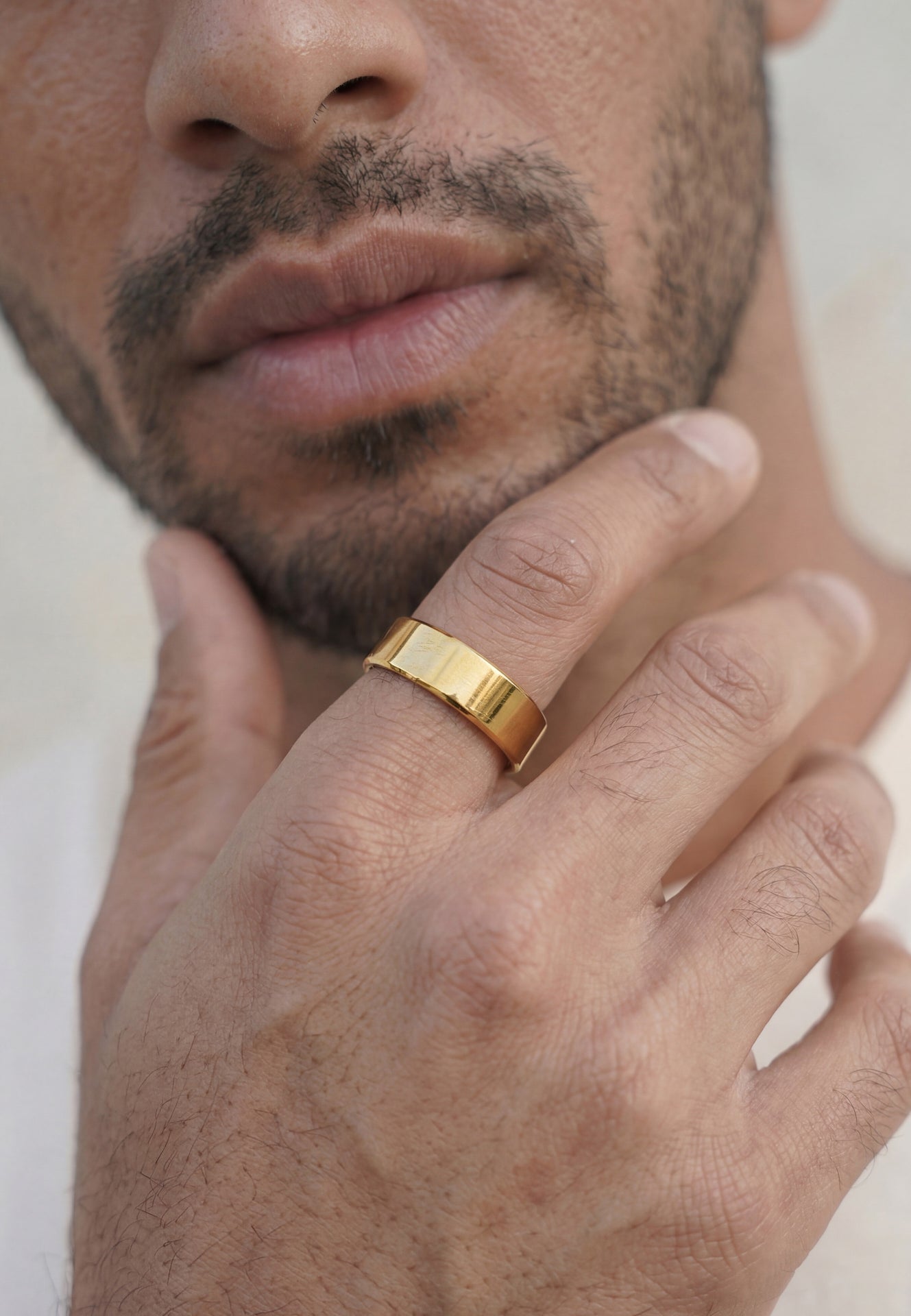 Close-up of a man's hand wearing a gold ring with a blurred background