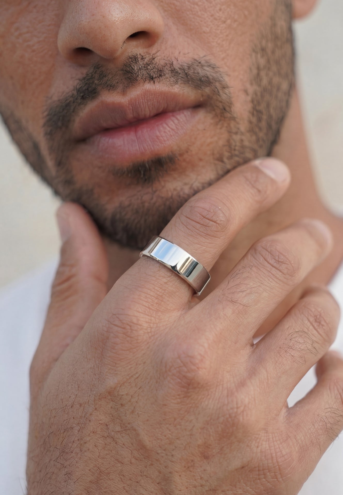 Close-up of male model wearing Akitsune Liber silver ring, featuring a polished minimalist band with a sleek contemporary design.