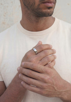 Male model wearing a minimalist silver Liber ring by Akitsune, showcasing a polished modern band with a clean, understated design.