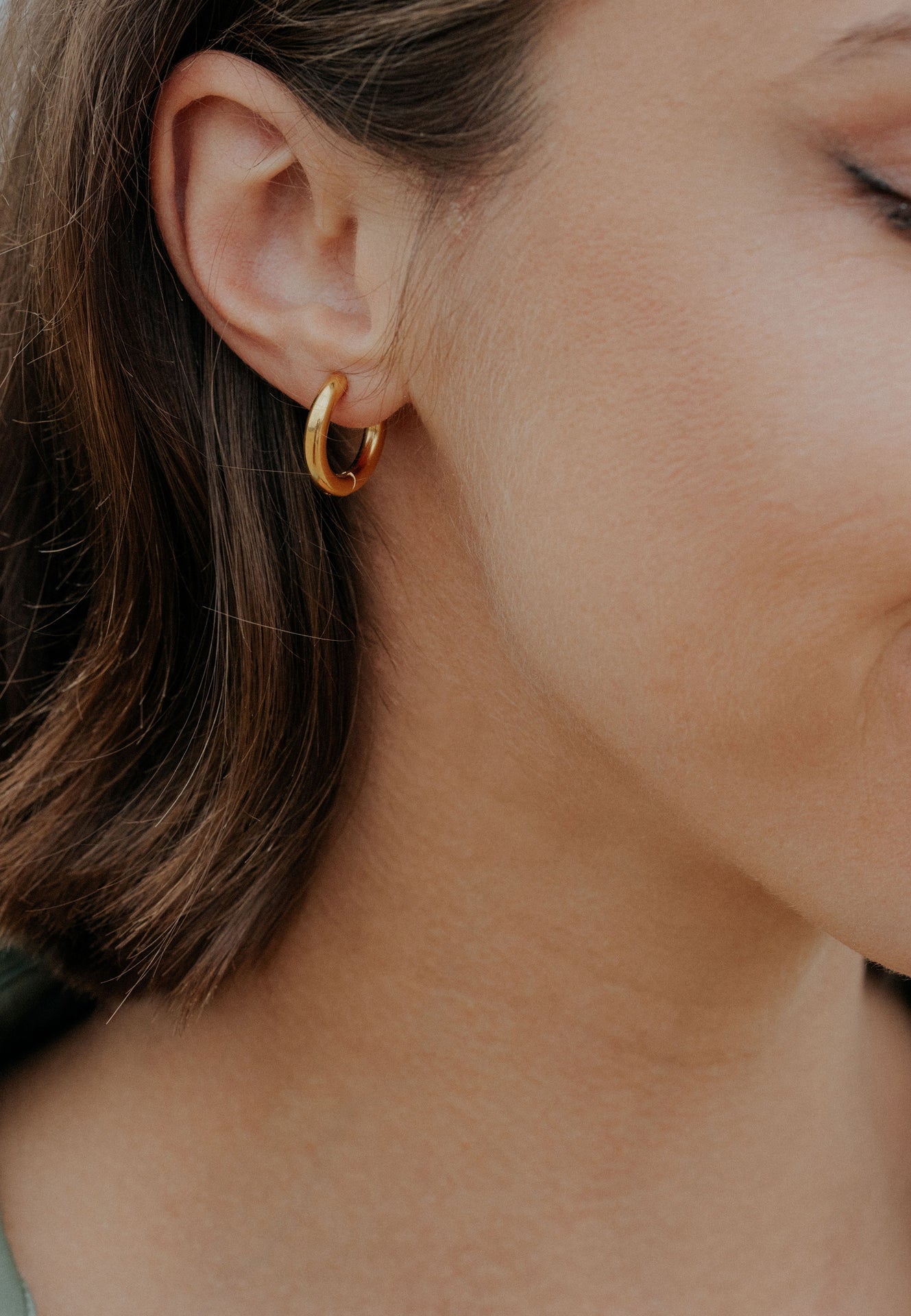 Close-up of a person wearing a gold hoop earring.