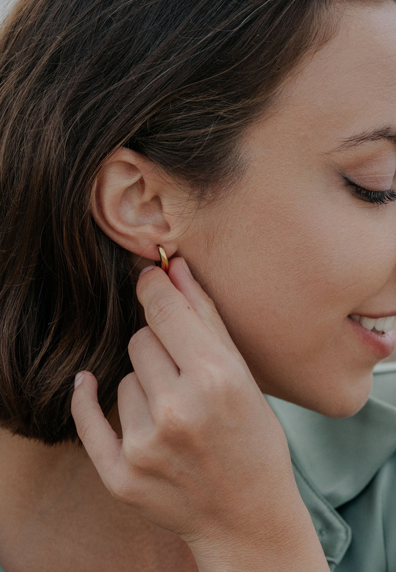 Woman adjusting a gold earring on her ear