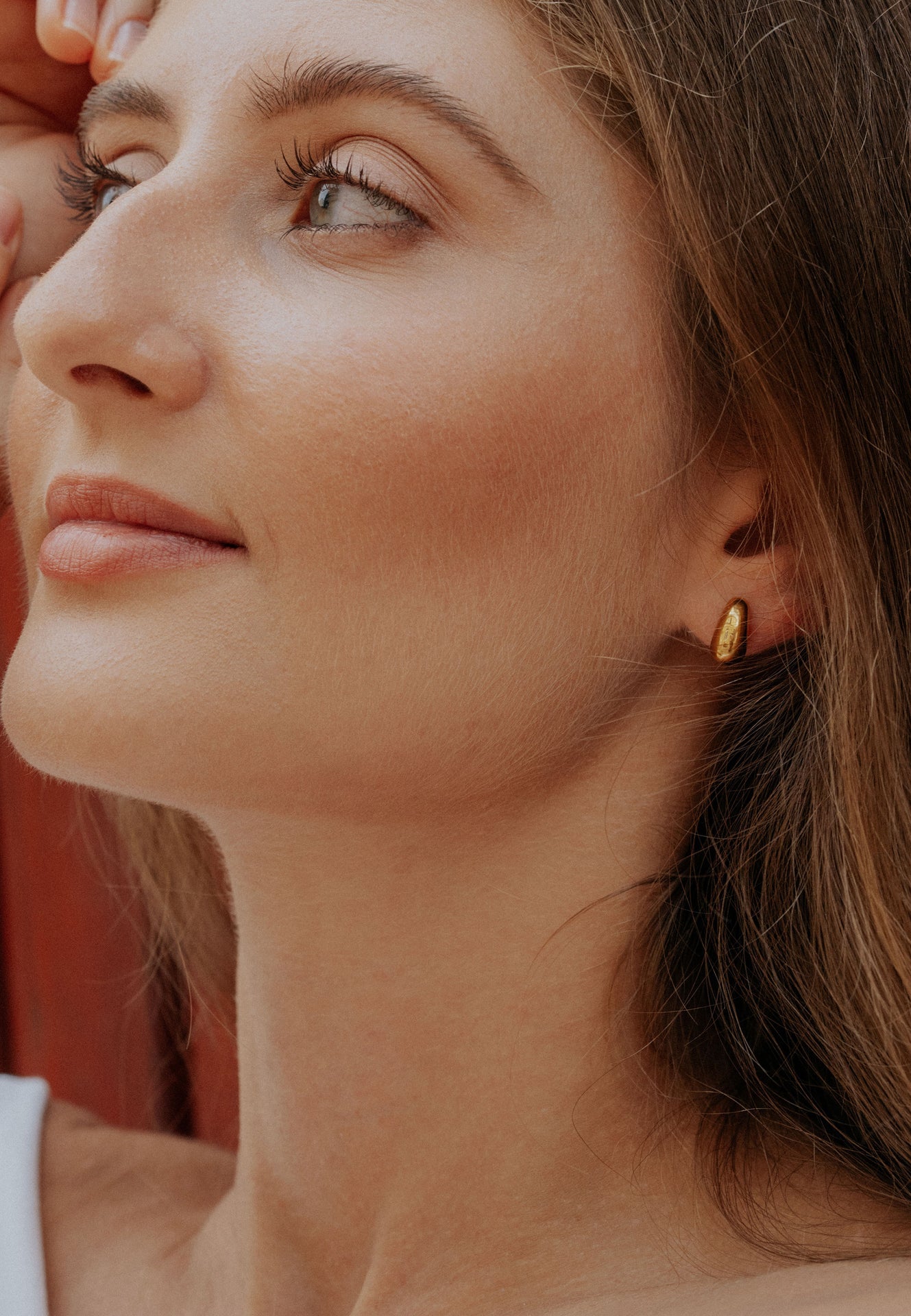 Close-up of a woman wearing a gold earring with a blurred background