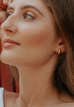 Close-up of a woman wearing a gold earring with a blurred background