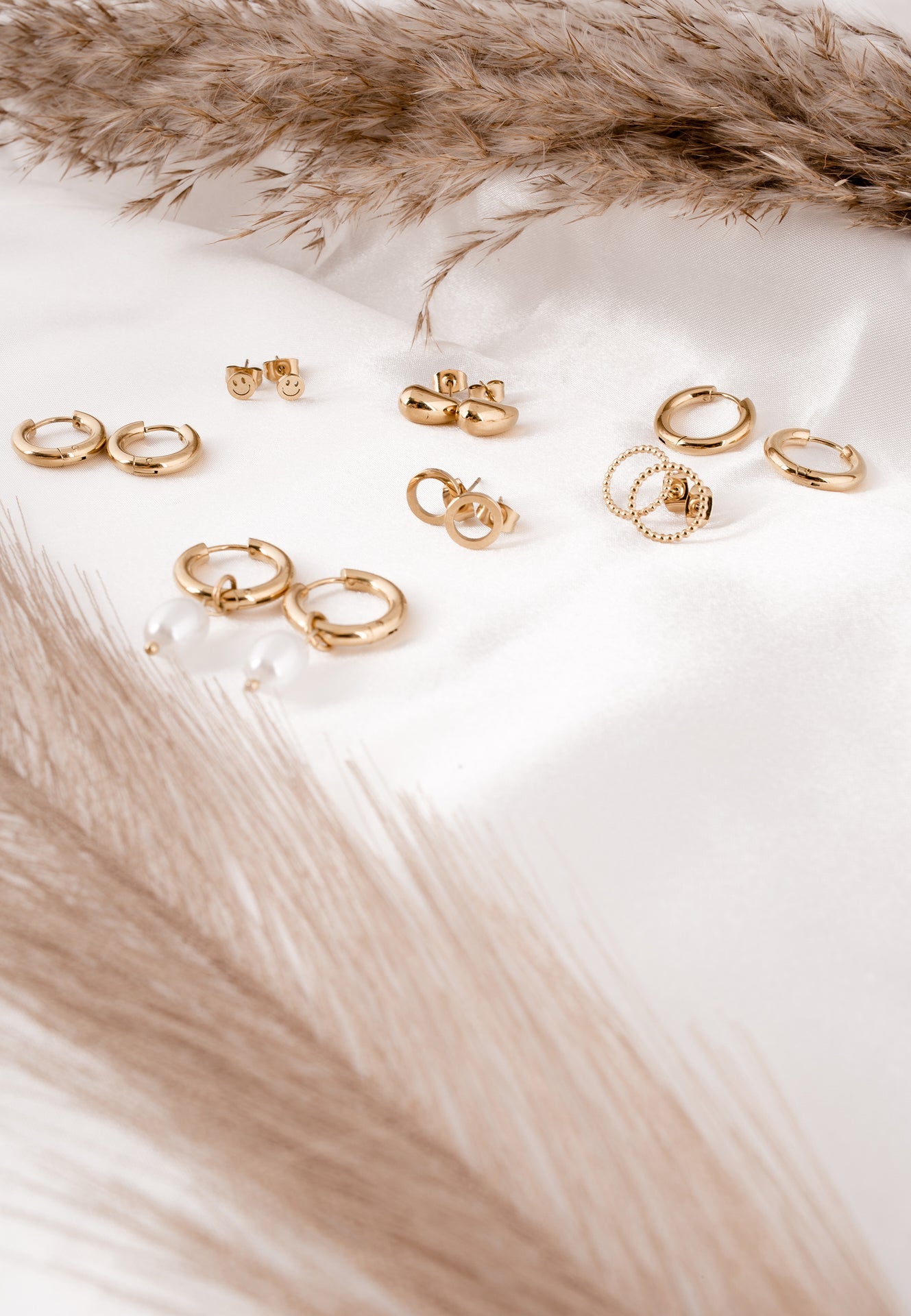 Gold earrings on a white surface with fur accents